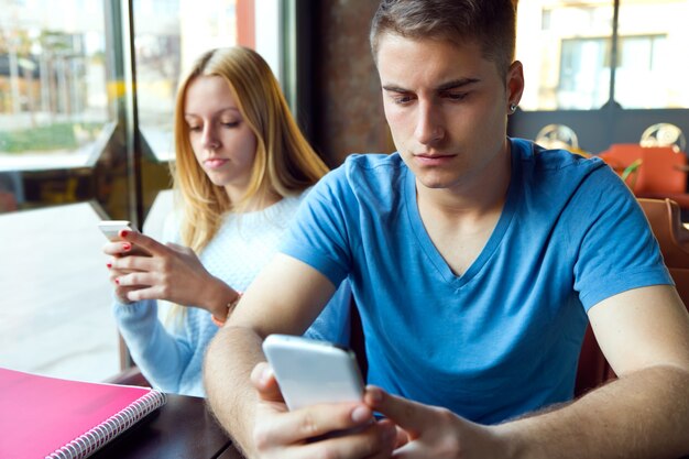 Grupo de amigos usando el teléfono móvil en el café.