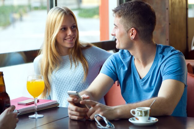 Grupo de amigos usando el teléfono móvil en el café.