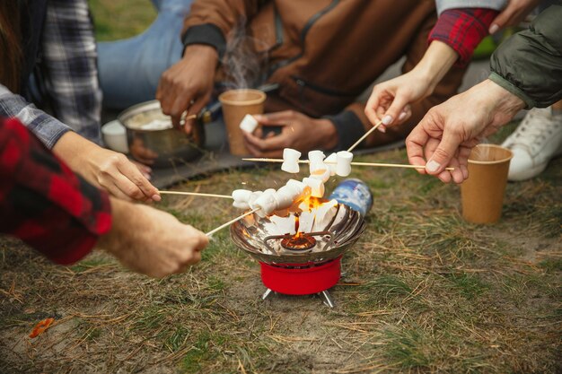 Grupo de amigos en un viaje de campamento o senderismo en día de otoño. Hombres y mujeres con mochilas turísticas con descanso en el bosque.