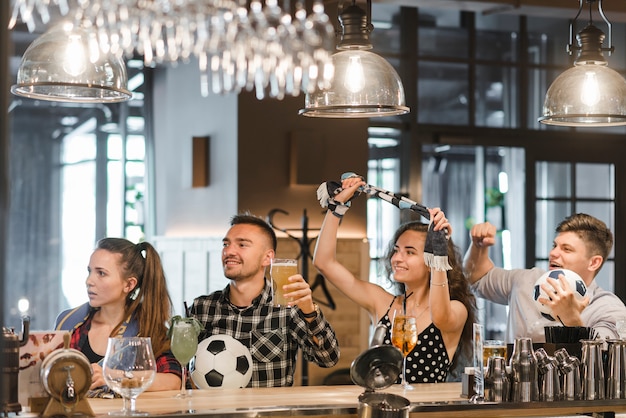 Grupo de amigos viendo deporte juntos en el bar