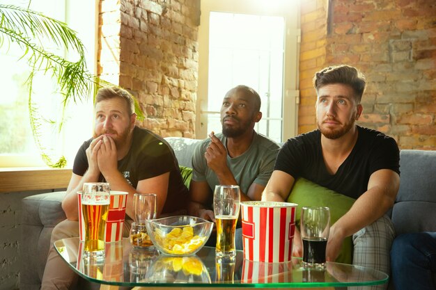 Grupo de amigos viendo el juego en la televisión en casa. Aficionados al deporte que pasan tiempo y se divierten juntos