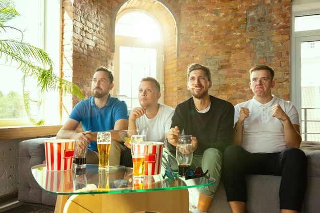 Grupo de amigos viendo el juego en la televisión en casa. Aficionados al deporte que pasan tiempo y se divierten juntos