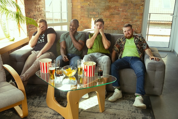 Grupo de amigos viendo el juego en la televisión en casa. Aficionados al deporte que pasan tiempo y se divierten juntos