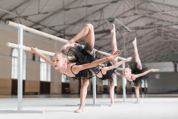 Grupo de chicas con su pierna cerca de la barra durante una clase de ballet