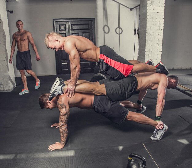 Grupo de chicos musculosos sin camisa haciendo flexiones.