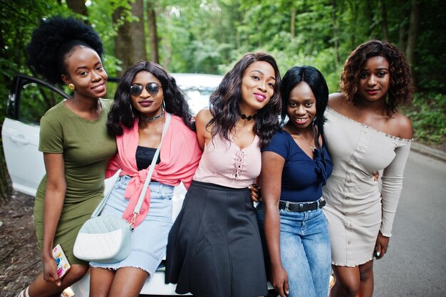 Grupo de cinco muchachas afroamericanas felices que se sientan en una capilla del coche