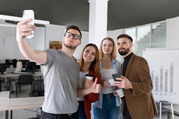 Grupo de compañeros de trabajo en la oficina tomando un selfie