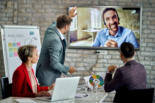 Grupo de compañeros de trabajo que tienen videoconferencia de negocios mientras trabajan en la oficina