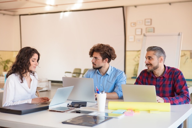 Grupo creativo con computadoras portátiles que discuten ideas en la sala de juntas