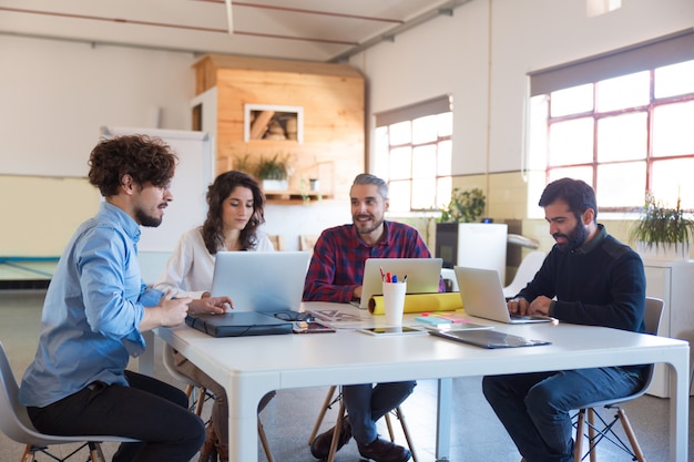 Grupo creativo que trabaja en el inicio, usando computadoras portátiles