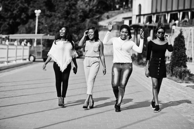 Grupo de cuatro chicas afroamericanas caminando en la ciudad en un día soleado