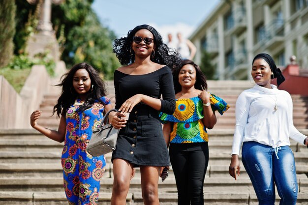 Grupo de cuatro chicas afroamericanas caminando por las escaleras de la ciudad