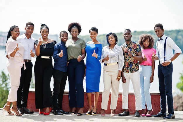 Grupo de diez personas afroamericanas posadas en la calle de la ciudad Gente de moda de África muestra el pulgar hacia arriba