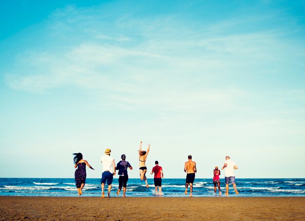 Grupo diverso de amigos corriendo a la playa