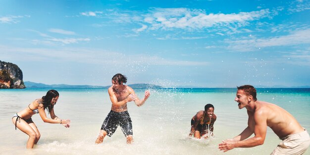 Grupo diverso de amigos jugando en el agua de la playa