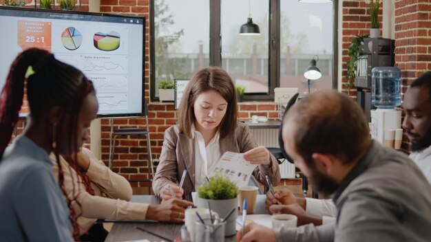 Grupo diverso de compañeros de trabajo discutiendo la estrategia empresarial en la oficina de inicio. Colegas que trabajan en la planificación y presentación de proyectos para el desarrollo y crecimiento de la empresa. Lluvia de ideas