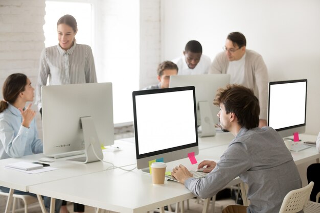 Grupo diverso de empleados corporativos trabajando juntos usando computadoras en la oficina