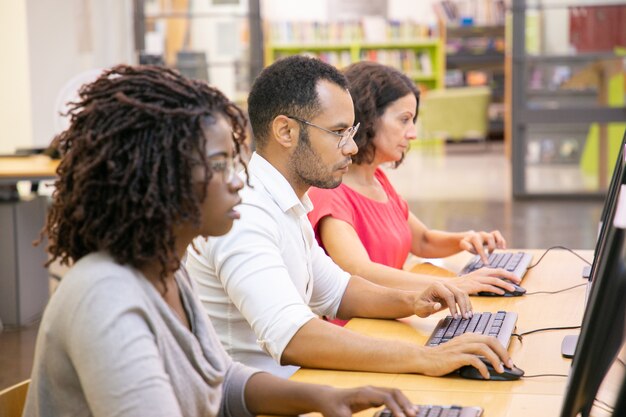 Grupo diverso de estudiantes adultos que trabajan en clase de informática