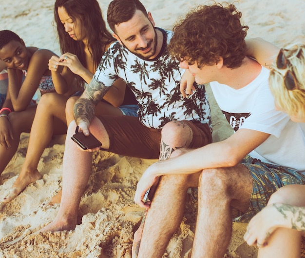 Foto gratuita grupo de diversos amigos sentados en la playa juntos