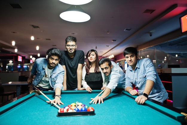 Grupo de elegantes amigos asiáticos usan jeans jugando al billar en el bar.