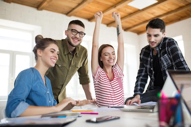 Foto gratuita grupo de emocionantes hombres y mujeres de negocios felizmente trabajando juntos en la oficina moderna jóvenes emocionales y alegres que pasan tiempo en el trabajo