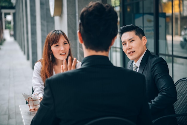 Grupo de empresarios asiáticos en el distrito comercial hablando de nuevos negocios y economía en una ubicación al aire libre