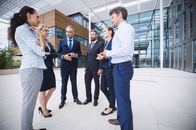 Grupo de empresarios interactuando fuera del edificio de oficinas