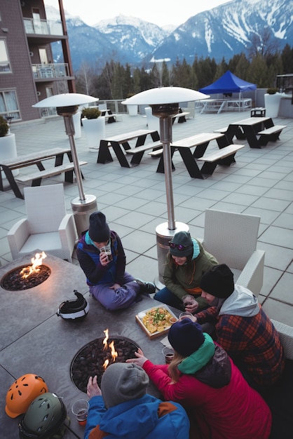 Foto gratuita grupo de esquiadores frotándose las manos cerca de la chimenea