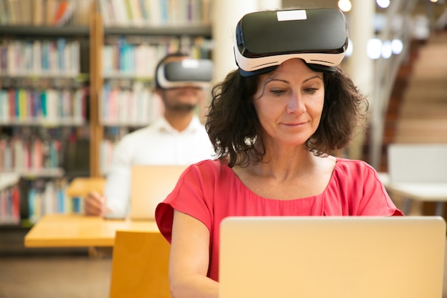 Grupo de estudiantes adultos que usan auriculares VR en clase de informática