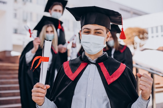 Grupo de estudiantes celebrando juntos la graduación y con máscaras faciales