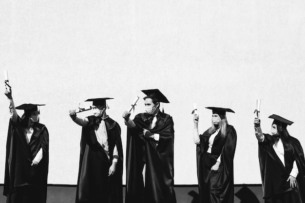 Foto gratuita grupo de estudiantes celebrando juntos la graduación y con máscaras faciales