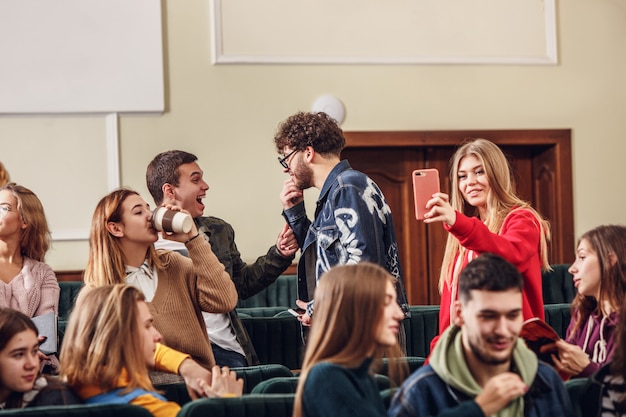 El grupo de estudiantes felices alegres sentados en una sala de conferencias antes de la lección