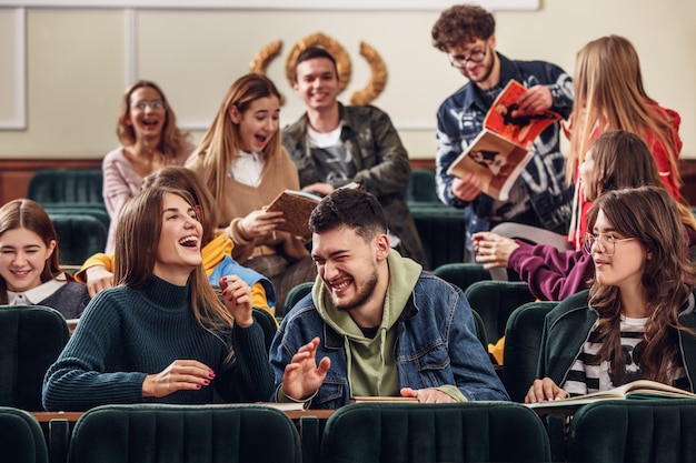 Foto gratuita el grupo de estudiantes felices alegres sentados en una sala de conferencias antes de la lección