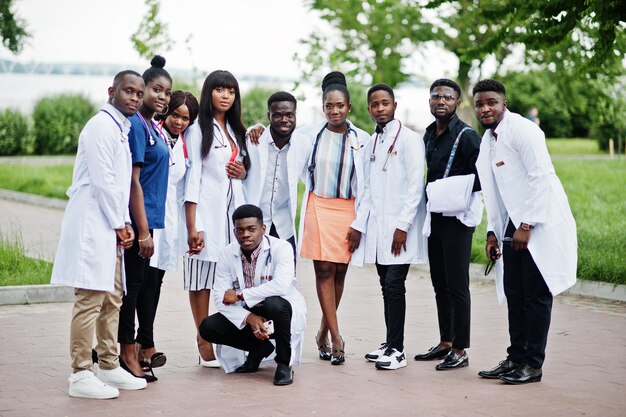 Grupo de estudiantes de medicina africanos posaron al aire libre en batas blancas de laboratorio