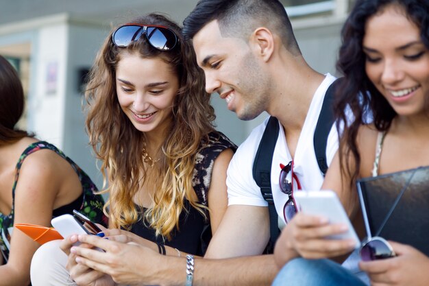 Un grupo de estudiantes que se divierten con smartphones después de clase.