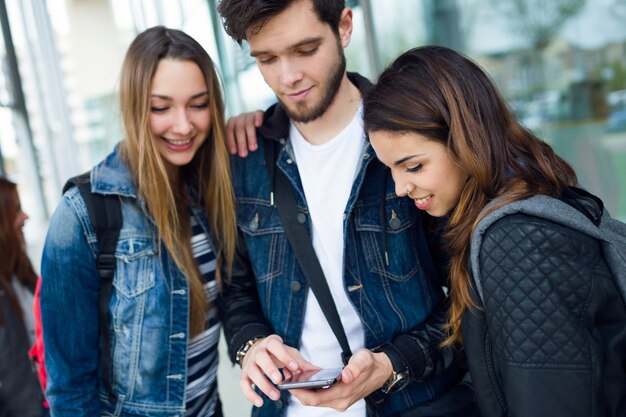 Un grupo de estudiantes que se divierten con smartphones después de clase.