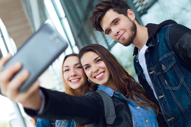 Un grupo de estudiantes que se divierten con smartphones después de clase.