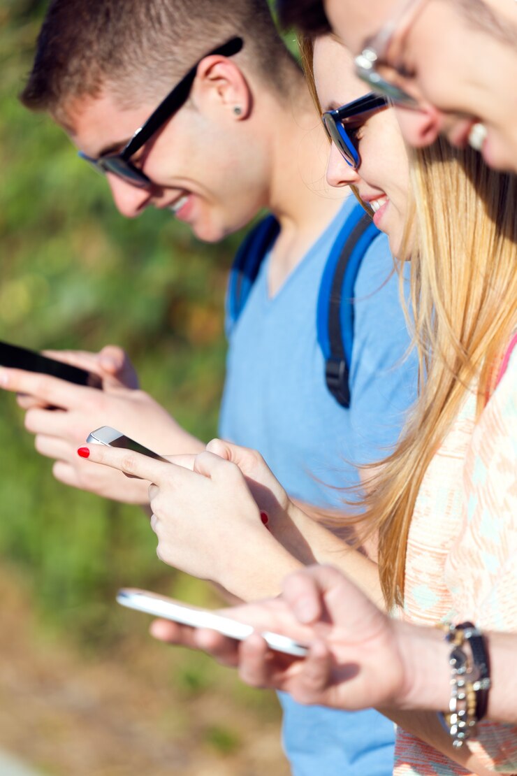 Foto gratuito un grupo de estudiantes que se divierten con smartphones después de clase.