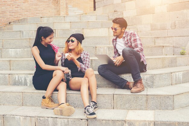 Grupo de estudiantes que se sientan inconformista en una escalera hablando y rel