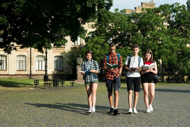 Grupo de estudiantes de secundaria leyendo mientras caminan
