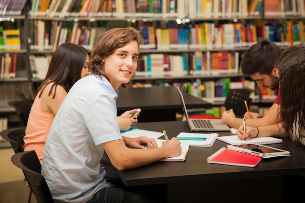 Grupo de estudiantes universitarios trabajando juntos en la biblioteca escolar