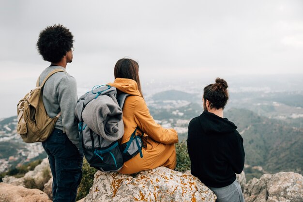 Grupo de excursionistas masculinos y femeninos sentado en la roca mirando la vista a la montaña