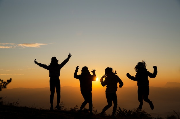 Grupo de gente joven feliz que salta en la colina. Mujeres jóvenes disfrutando