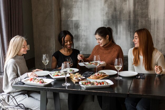 Grupo de hermosas mujeres jóvenes disfrutando de una cena juntos