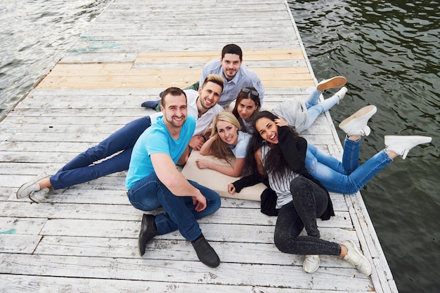 Grupo de hermosos jóvenes en el muelle, la satisfacción de los amigos crea vida emocional.