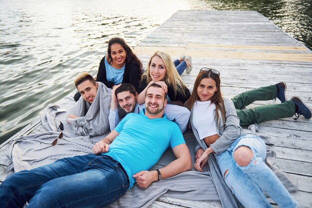 Grupo de hermosos jóvenes en el muelle, la satisfacción de los amigos crea vida emocional.