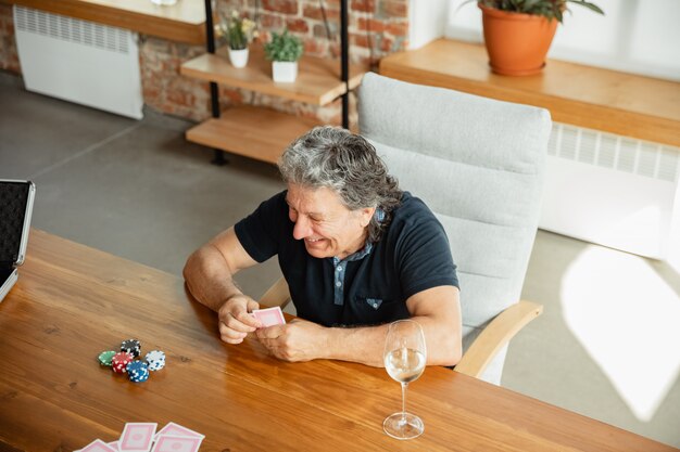 Grupo de hombre maduro feliz jugando a las cartas y bebiendo vino