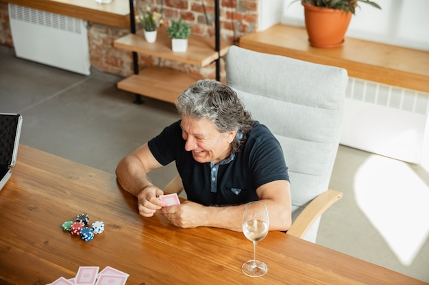 Grupo de hombre maduro feliz jugando a las cartas y bebiendo vino