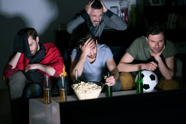 Grupo de hombres bebiendo cerveza y viendo fútbol en la televisión