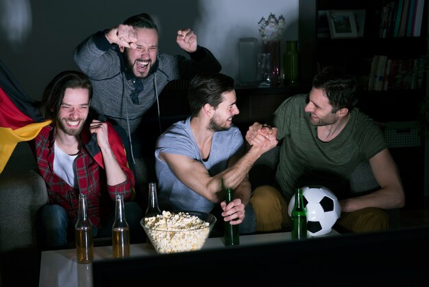 Grupo de hombres bebiendo cerveza y viendo fútbol en la televisión